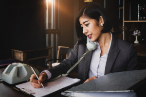 A woman taking notes while on the phone