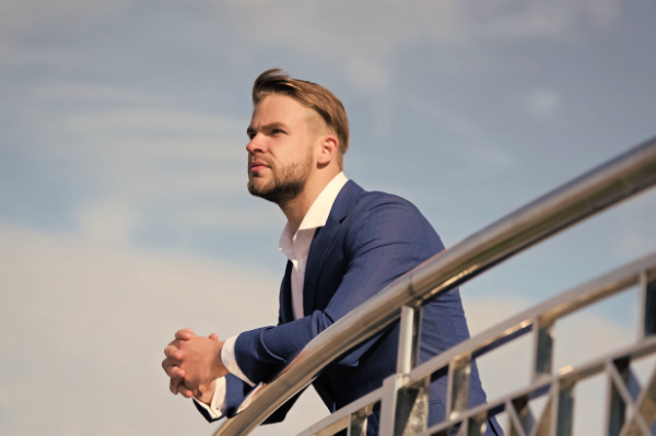 Burnout can sneak up, especially in government roles. With a few smart strategies, you can protect your well-being and set yourself up for a happier, healthier year.. A bearded man in a blue suit rests his arms on a railing. He is enjoying the sunshine during a break at work. 