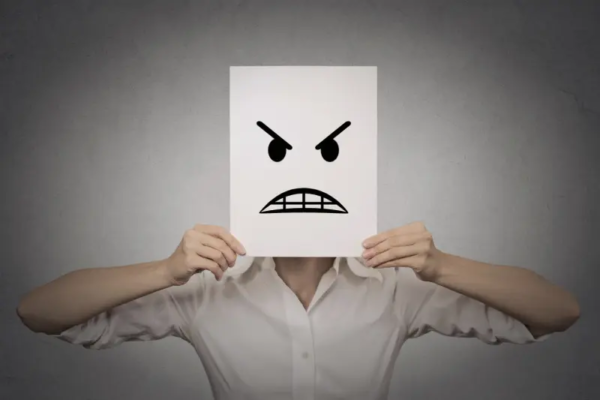 Person holding a sheet of paper with an angry face illustration in front of their face, representing public frustration or criticism toward a government office