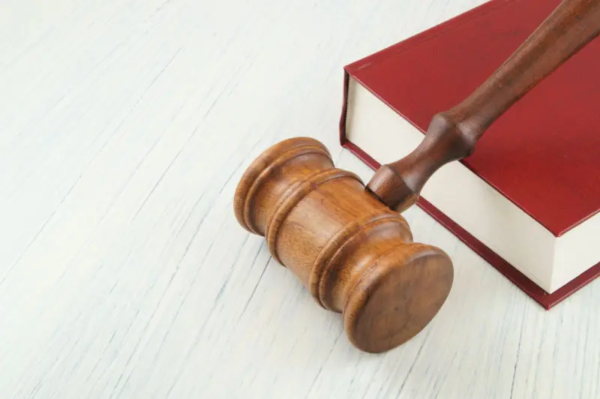 Wooden gavel resting on a red hardcover book, representing parliamentary procedure and Robert’s Rules of Order used in board and committee meetings