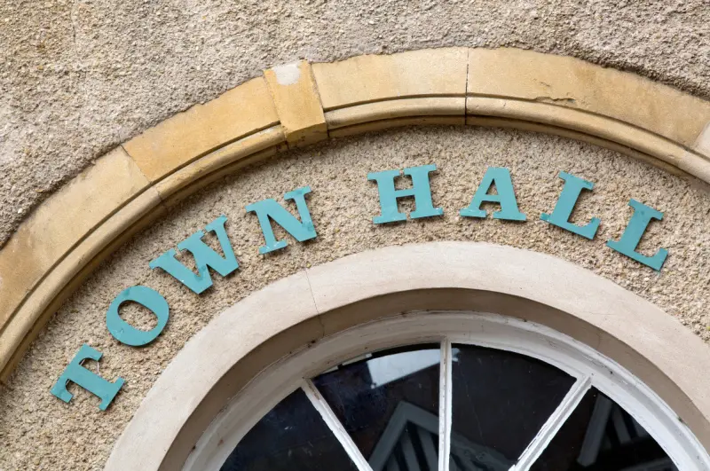 Stone archway with "Town Hall" lettering above an arched window, representing the seat of local government where a municipal charter sets the rules of operation.